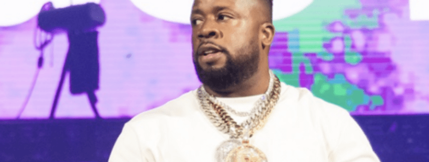 Man wearing chains on stage with colorful background.